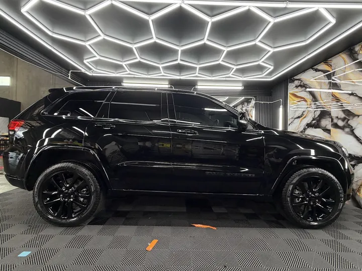 Black SUV in a studio under hexagonal ceiling lights with dark tinted windows.