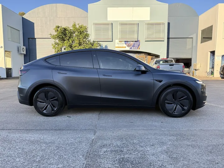 Matte grey crossover parked side-on with dark tinted side windows.