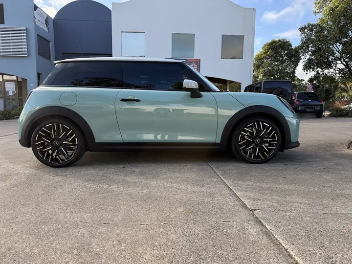 Mint green three-door hatch parked side-on with a white roof and patterned alloy wheels.