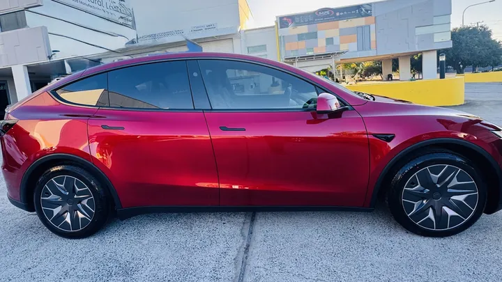 Red crossover parked side-on outdoors with glossy paint and large alloy wheels.