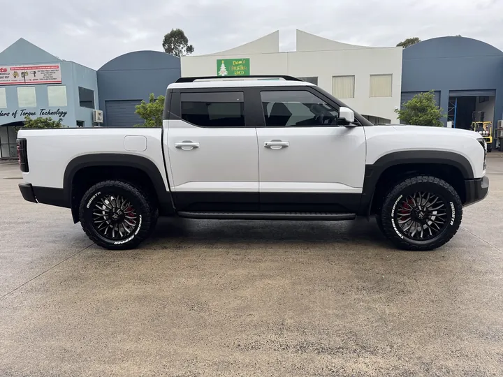White dual cab ute parked side-on with dark tinted cabin windows.
